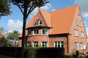 Ein rotbacksteinhaus mit steilem Dach, zahlreichen Fenstern und einer sichtbaren Satellitenschüssel.