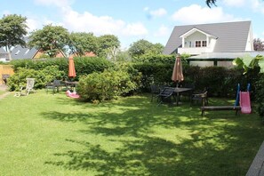 Ein Garten mit Tisch und Stühlen, einer Rutsche und einem Haus im Hintergrund.