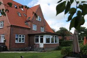 Ein Ziegelhaus mit rotem Ziegeldach, einem Erkerfenster und einer kleinen Veranda.