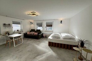Ein modernes Zimmer mit Bett, Schreibtisch und einer Couch.