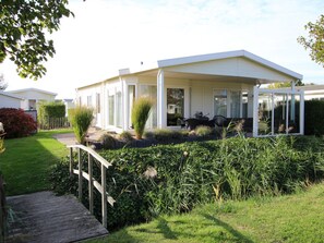 Et moderne hus med en overdækket terrasse, træterrasse og have.