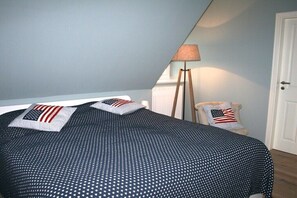 Ein Schlafzimmer mit Bett, Kissen, einer Lampe und einem Sessel.