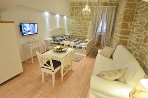 Um quarto acolhedor com uma cama, uma mesa de jantar com cadeiras, uma televisão e uma parede de pedra.