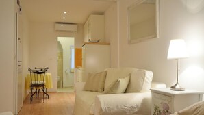 A bedroom with a bed, a bedside table with a lamp, a chair, a table with a yellow tablecloth, and a wardrobe. - Studios Villa Rossella 4 (Rovinj)