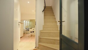A staircase leading to a room with a glass door, a dining area with a table and chairs, and a stone wall in the background. - Studios Villa Rossella 4 (Rovinj)