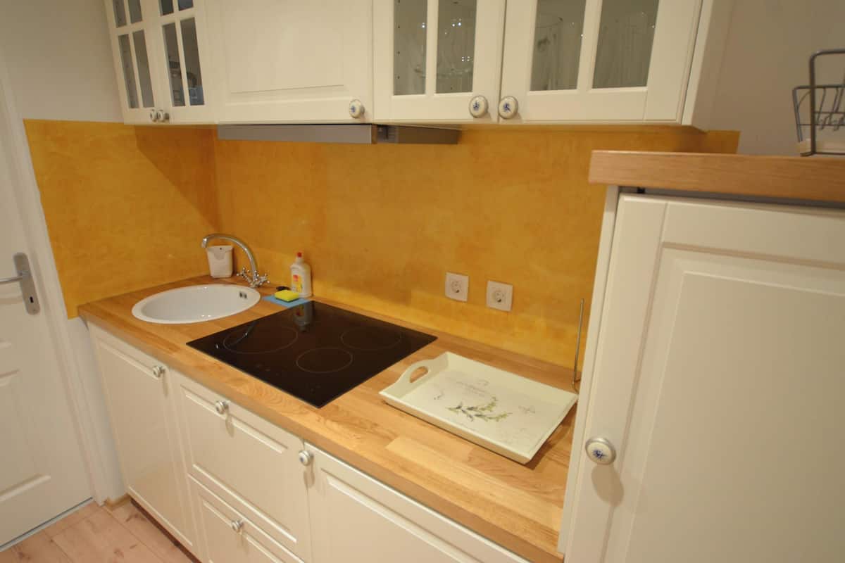 Cozinha com armários brancos, bancada de madeira, pia e fogão.