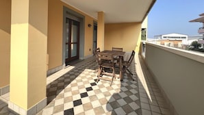 A balcony with a checkered floor, a wooden table and chairs, and a door. - Well Equipped Holiday Home in Grado (Grado)