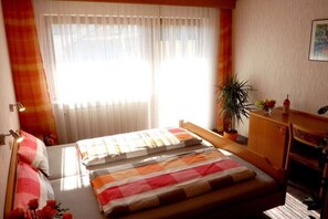 A bedroom with a bed, a desk, a chair, a potted plant, and a window with curtains. - Herbert Ziegler Winery "Eulbusch" 2 (Maikammer)