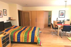 A bedroom with a bed, a desk, and a chair. There are wooden wardrobes and a door leading to another room. - 4 in the Weser I building (Cuxhaven-Döse)
