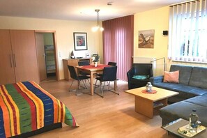 A room with a bed, a sofa, a dining table with chairs, a coffee table, and a radiator. - 4 in the Weser I building (Cuxhaven-Döse)