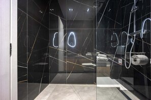 Ein modernes Badezimmer mit Glastrennwand, Duschbereich und Toilette, die durch das Glas sichtbar ist.
