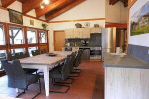 Eine Küche mit Holzschränken, einem Esstisch mit Stühlen und einem Kühlschrank.