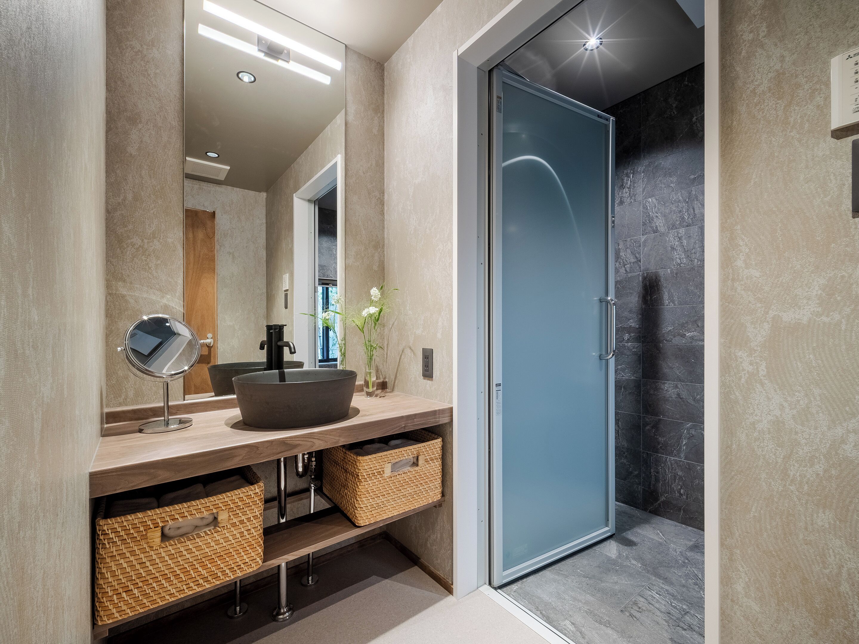 A modern bathroom with a round sink, a mirror, and a glass shower door.