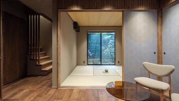 A modern interior with a wooden floor, a glass table, and a sliding door leading to a garden.