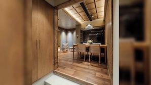 Una cocina moderna con armarios de madera, un comedor con mesa y sillas, y una escalera que sube a un nivel superior.