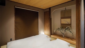 Un dormitorio con cama, techo de madera y una estantería anclada a la pared con un florero.