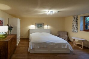 A bedroom with a bed, bedside lamps, a chair, a small table, a cabinet, and a window with curtains. - Gommerscheid Hunting Lodge (Ehlscheid)