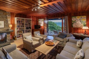 A cozy living room with a fireplace, a large bookshelf, and a comfortable seating area. - Gommerscheid Hunting Lodge (Ehlscheid)