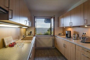 A modern kitchen with a view, equipped with a sink, stove, and various appliances. - Gommerscheid Hunting Lodge (Ehlscheid)