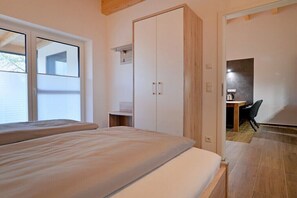 Ein Schlafzimmer mit Bett, Kleiderschrank, Schreibtisch und Stuhl.