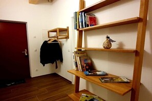 Une pièce avec une bibliothèque en bois, un porte-manteau et une porte.