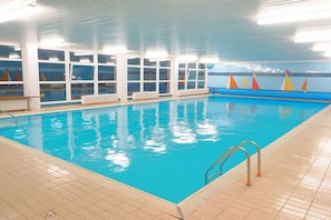Ein Innenpool mit klarem, blauen Wasser, geflieste Wände und ein gefliester Boden.