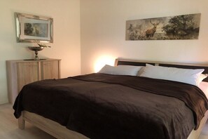 Ein Schlafzimmer mit einem Bett, einem Nachttisch, einem gerahmten Bild und einem Gemälde an der Wand.
