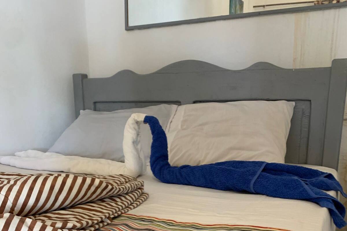 A bed with striped bedding, pillows, and a blue towel.