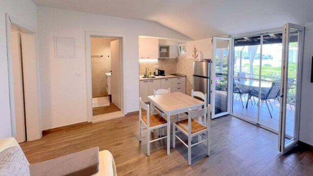 A compact living space with a kitchen, dining area, and a sliding glass door leading to a balcony. - Apartments Vicelić (Orebic)