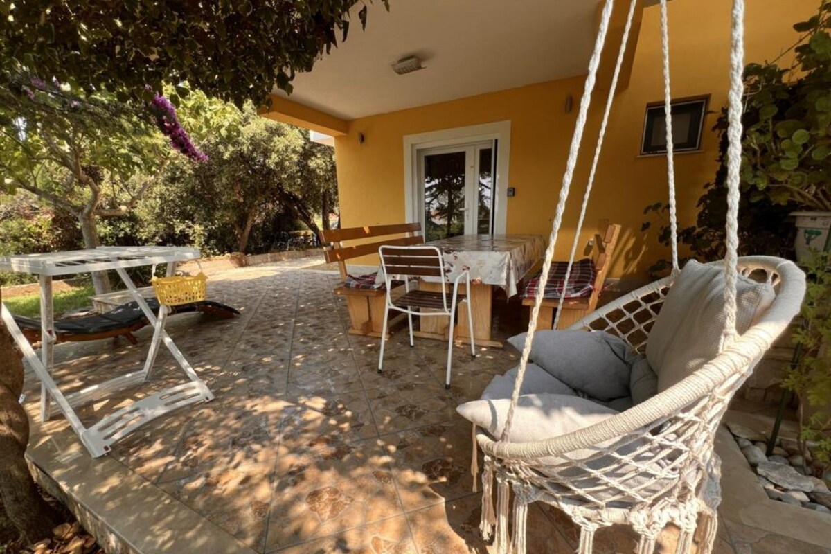 A patio with a swing chair, a table, and a bench.