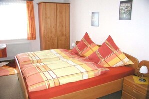 Ein Schlafzimmer mit einem Bett, einem Holzschrank, einem Nachttisch und einer Lampe.