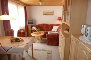 Ein kompakter Wohnbereich mit Esstisch, Sofa und kleinem Fernseher.