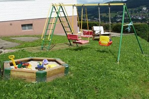 Un parque infantil con columpios y un arenero.