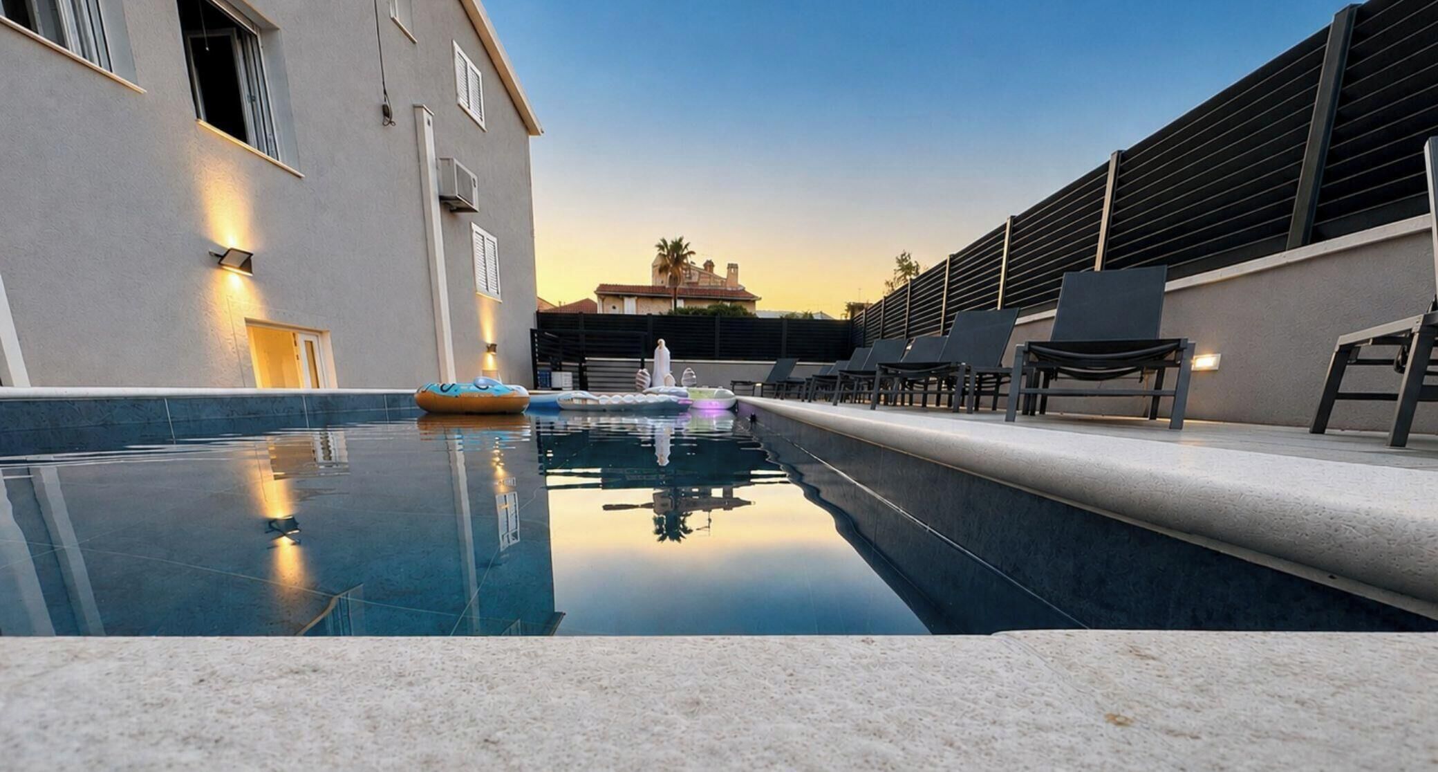 Une piscine avec des chaises longues et un bâtiment au design moderne.