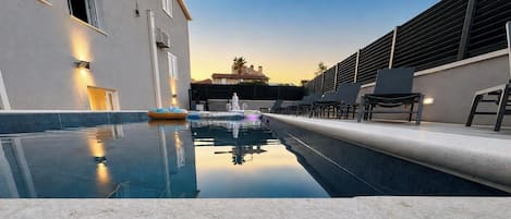 A swimming pool with lounge chairs and a building with a modern design.