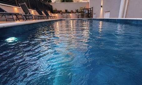 A swimming pool with lounge chairs and a staircase leading to an upper level.