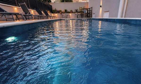 Una piscina con sillas de descanso y una escalera que lleva a un nivel superior.