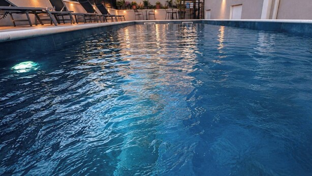 A swimming pool with lounge chairs and a staircase leading to an upper level. - Villa Dante (Trogir)