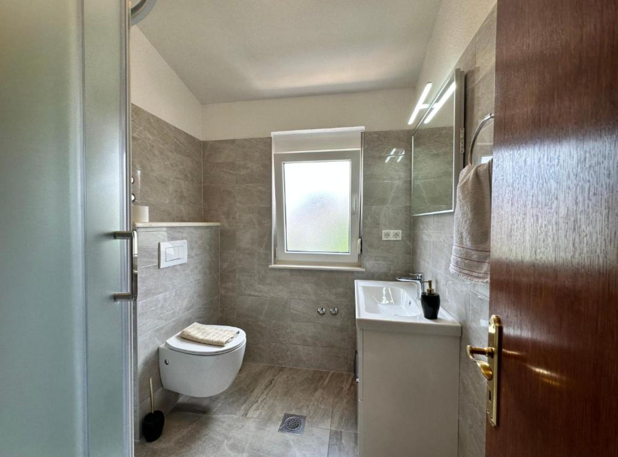 A bathroom with a toilet, sink, and window.