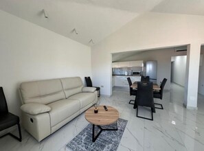 Una sala de estar moderna con un sofá, una mesa de centro y un comedor con sillas y una mesa.