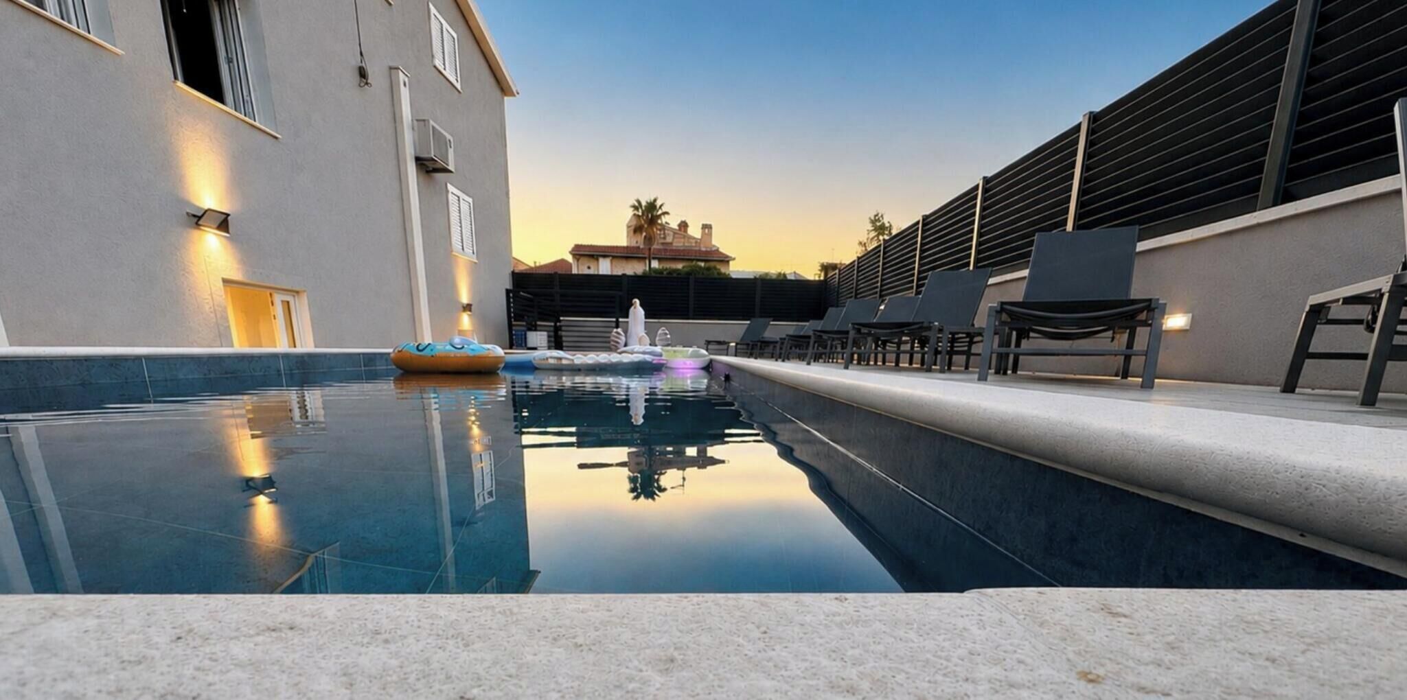 A swimming pool with lounge chairs and a building with a modern design.