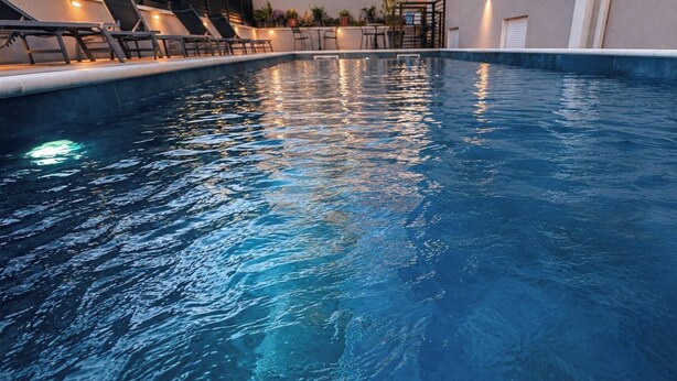 Una piscina con sillas de descanso y una escalera que lleva a un nivel superior.