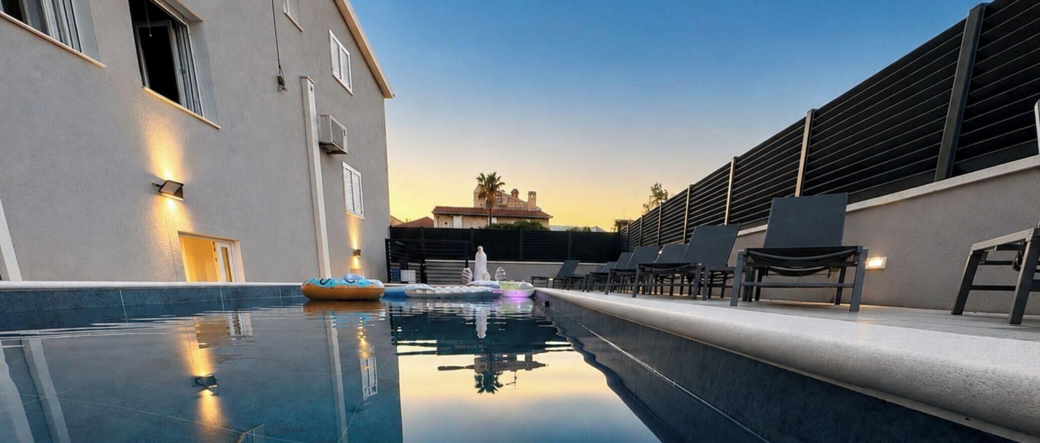 A swimming pool with lounge chairs and a building with a modern design.