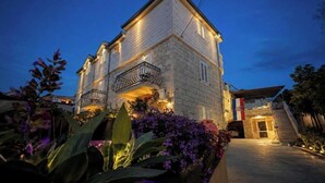 A two-story building with a balcony, surrounded by flowering plants. - Villa Dante (Trogir)