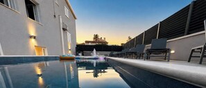 Una piscina con sillas de descanso y un edificio de diseño moderno.