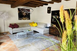 A living room with a sofa, two side tables, a painting, a bookshelf, and a tall plant. - Holiday home with 2 bedrooms (Mainz-Kostheim)