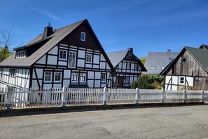 A traditional half-timbered house with a white picket fence, a sloped roof, and a chimney. - Holiday home with 2 bedrooms (Olsberg- Bruchhausen)