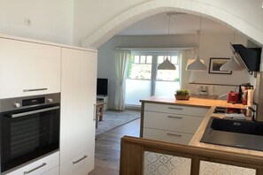 Eine moderne Küche mit weißen Schränken, einem eingebauten Ofen, einer Holz Arbeitsplatte und einem Spülbecken.