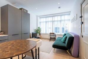 A modern living space with a dining table, sofa, and TV. - Chic 1BDR Retreat in St Johns Wood (Greater London)
