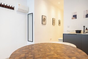 A modern kitchen with a round wooden table, a built-in oven, and wall-mounted artwork. - Chic 1BDR Retreat in St Johns Wood (Greater London)